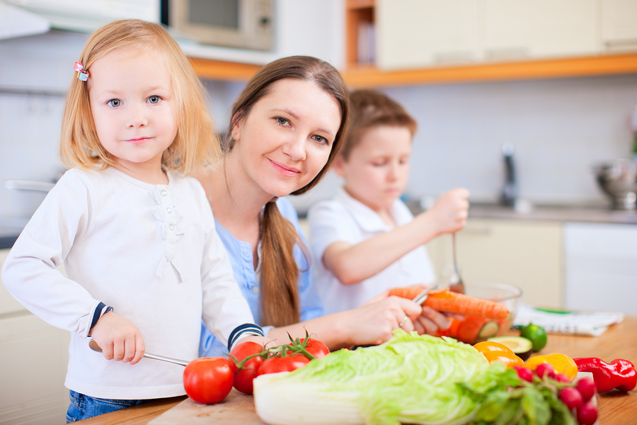 Young mother and her two kids making vegetable salad